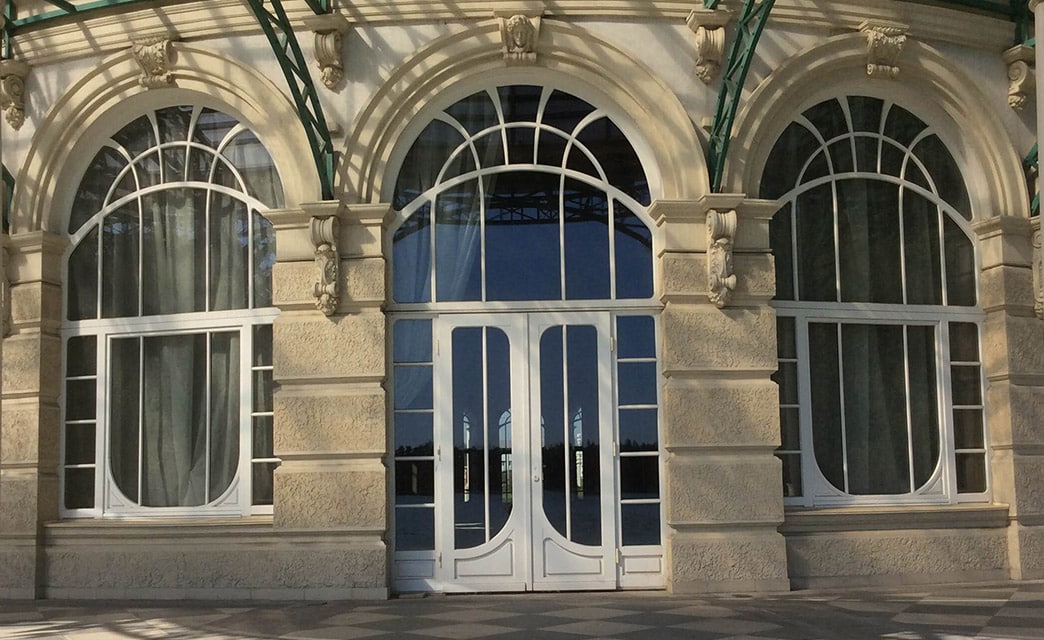 Eingangstür und links und rechts davon zwei Fenster. Alles aus weißem Holz und mit vielen, geschwungenen Glaselementen.